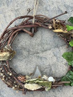 a wreath made out of twigs, leaves and other things on top of a rock