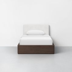 a bed with a wooden frame and white sheets on the headboard, sitting in front of a wall