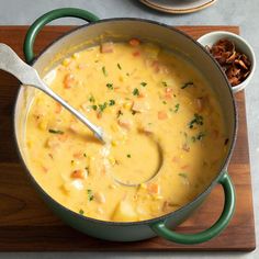 a pot filled with soup on top of a wooden cutting board next to other dishes