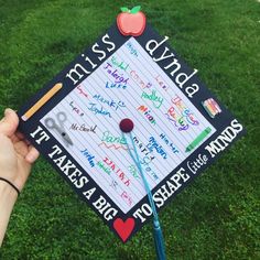 a hand holding a graduation cap with writing on it and an apple in the middle