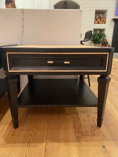 a black and gold coffee table on display in a room with wood floors, white walls and furniture