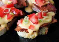 a black plate topped with slices of bread covered in cheese and toppings