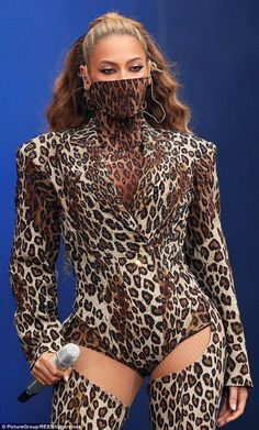 a woman in a leopard print bodysuit with her hands on her hips and one hand under her face