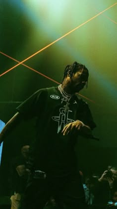 a man with dreadlocks standing on stage in front of green and yellow lights