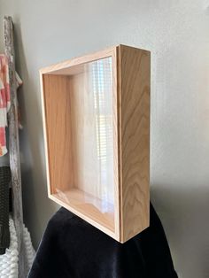 a wooden box sitting on top of a black cloth covered chair next to a window