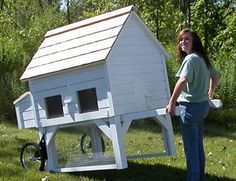 a woman standing next to a white chicken house