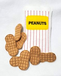 three cookies sitting on top of a white cloth covered in peanut butter next to a bag of peanuts