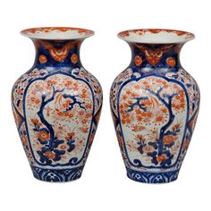 two large vases sitting next to each other on a white surface with orange and blue designs