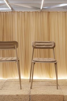 two chairs sitting next to each other in front of a curtained wall and floor