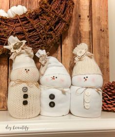 three snowmen sitting next to each other in front of a wreath on top of a mantle