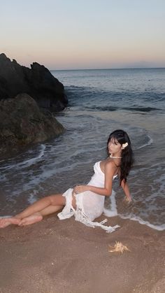 a woman laying on top of a sandy beach next to the ocean