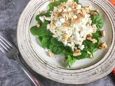 a white plate topped with spinach and nuts