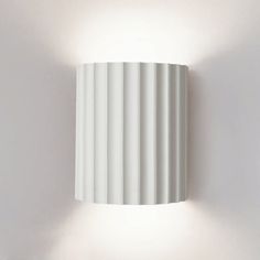 a white wall light mounted on the side of a wall