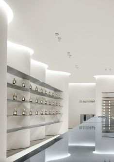 the interior of a store with white shelves and lights on each wall, along with candles