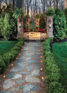 a stone path leads to an open gate in the middle of a lush green yard