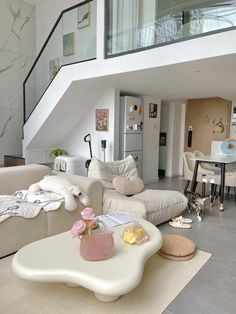 a living room filled with furniture and a stair case in the back drop down to the second floor