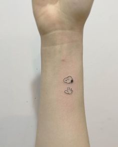 a person's arm with a small dog tattoo on the left side of their wrist