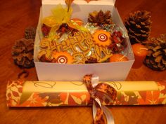 a box filled with lots of treats on top of a wooden table next to pine cones