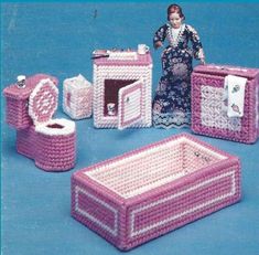 crocheted dollhouse furniture and accessories displayed on blue surface with woman in background