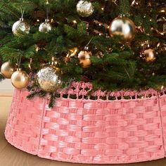 a pink basket under a christmas tree with gold ornaments on the top and below it