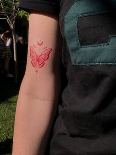 a person with a red butterfly tattoo on their left arm and the other arm behind them