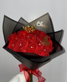 a bouquet of red roses with a tiara on top is wrapped in black paper