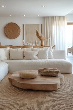 a living room filled with white couches and pillows on top of a wooden table