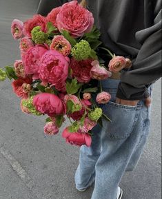 a person holding a bouquet of flowers in their hands on the street with cars behind them