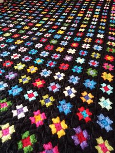 a multicolored crocheted blanket on top of a bed in a room