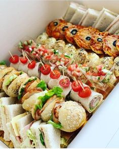 many different types of food are on display in a white box, including sandwiches and pizzas