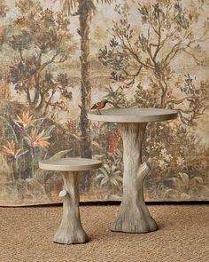 two small tables sitting next to each other on top of a carpeted floor in front of a painting