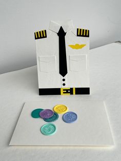 an airplane pilot's uniform and some buttons on a white tablecloth with a card