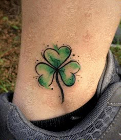 a green four leaf clover tattoo on the side of a woman's foot,