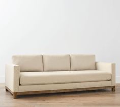 a white couch sitting on top of a hard wood floor next to a white wall