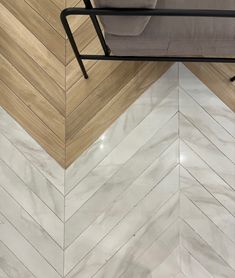 a chair sitting on top of a wooden floor next to a white tiled wall with herringbone pattern