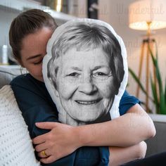 a woman hugging a pillow with an image of a smiling elderly woman on it's face