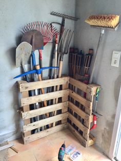 a wooden crate filled with gardening tools on top of a floor next to a wall