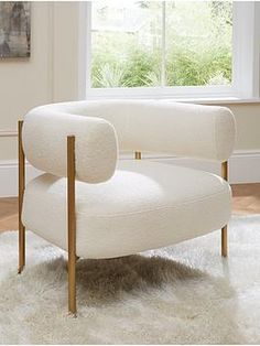 a white chair sitting in front of a window on top of a shaggy area rug