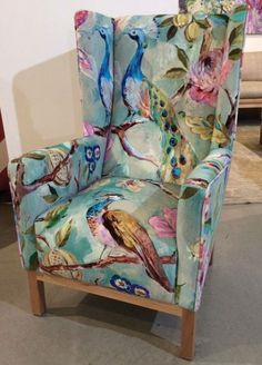 a colorful chair sitting on top of a floor next to a wall with flowers and birds painted on it