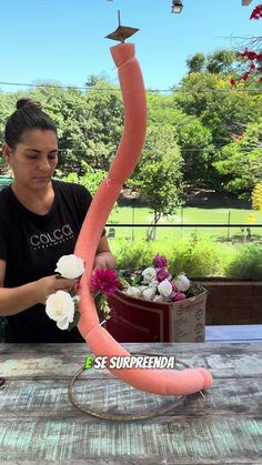 a woman is making a fake pink flamingo