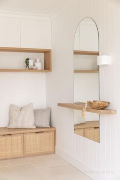 a white room with some shelves and a mirror on the wall next to a bench