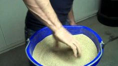 a man mixing sand in a blue bucket