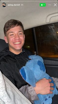 a man sitting in the back seat of a car holding a stuffed animal