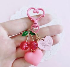 a pink heart shaped keychain with two cherries attached to it's sides