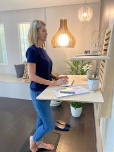 a woman standing at a desk using a laptop computer