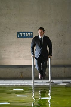 a man in a suit and tie is standing on a metal railing with his legs crossed