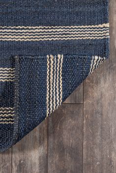 a blue and white striped rug laying on top of a wooden floor next to a piece of wood