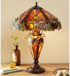 a table lamp sitting on top of a wooden table next to a vase and bottle