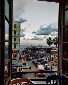 an open window looking out onto a parking lot with cars parked on the street and palm trees