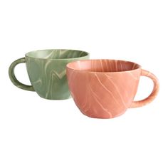 two marbled coffee mugs sitting next to each other on a white background, one is green and the other is pink